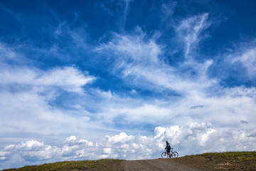 Cyclist on the horizon on a background of clouds.