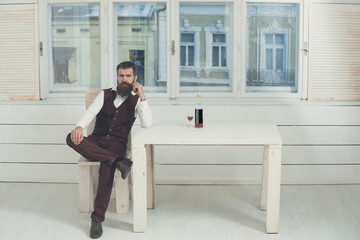 Man sitting on chair at table with bottle and glass
