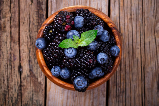 Blackberry and Blueberry with Mint. Fresh Berry in a wooden bowl on a wooden Vintage Background.Food or Healthy diet concept.Vegetarian.Copy space for Text.selective focus