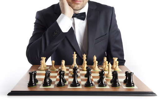 A smart man in a dark suit over the chessboard. Logical thinking