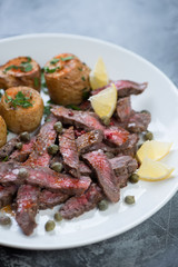 Grilled tagliata steak with baked potatoes, selective focus, close-up, vertical shot