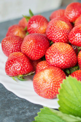Red strawberries and green leaves on a black background