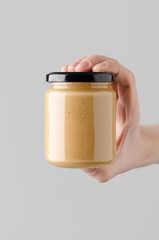 Peanut / Almond / Nut Butter Jar Mock-Up - Male hands holding a nut butter jar on a gray background