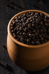 Black Pepper or Peppercorns in a Rustic Earthy Bowl. Vertical.