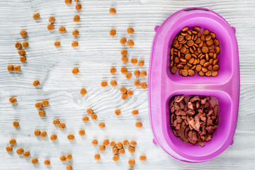 Animal food in bowl on wooden background top view