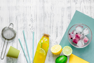 Bottle of fresh lemonade, fruits and ice cubes on wooden background top view copyspace