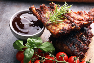 Spicy hot grilled spare ribs from a summer BBQ served with fresh tomatoes on an old vintage wooden...