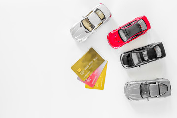 Choosing car concept. Toy cars and bank card on white background top view copyspace