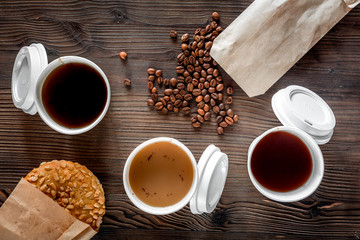 Coffee take out. Coffee cups with covers, coffee beans and cookies on wooden table backound top view