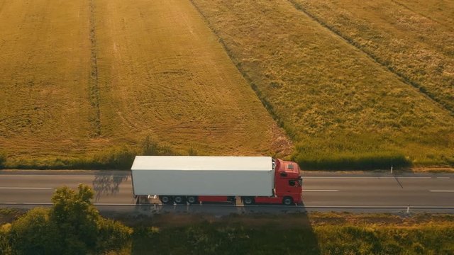 Aerial side shot of a truck on the road in beautiful countryside in the sunset light.
