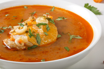 Chicken soup with noodles and vegetables in white bowl