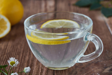 Delicious tea with lemon on a wooden background. A slice of lemon on the table. Water with lemon.