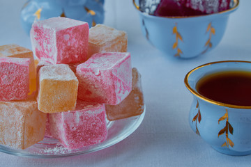 Delicious Turkish delight with tea on a wooden background