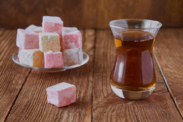Delicious Turkish delight with tea on a wooden background
