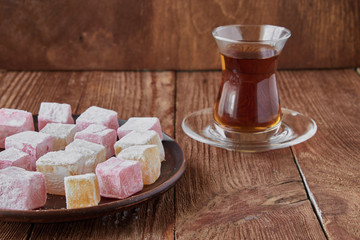 Delicious Turkish delight with tea on a wooden background
