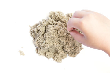 Child playing with kinetic sand. Hand of the child in the sand close up on a bright background