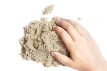 Child playing with kinetic sand. Hand of the child in the sand close up on a bright background