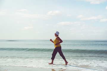 senior woman jogging on sea beach at the morning