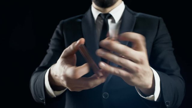 Close-up of a Suited Magician's Hands Performing Sleight of Hand Card Tricks, Fan Out Cards, Spinning One Card on a Finger. Background is Black. Shot on RED EPIC-W 8K Helium Cinema Camera.