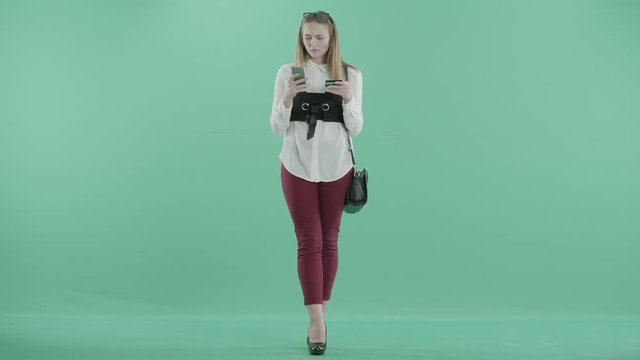 a girl stands with a card and a phone in hands