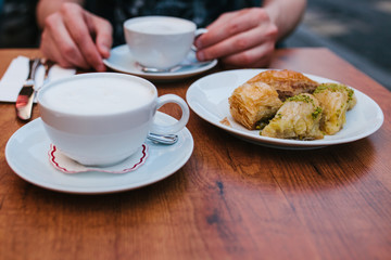 A man in a cafe eats coffee with a traditional oriental baklava dessert. Eastern food. Turkish dessert. Food.
