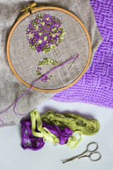 Вышивка в виде цветка на льняной ткани, натянутой на деревянные пяльцы, нитки мулине, ножницы