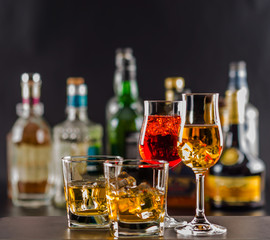 Colorful drink on the background of bottles in original shapes, cocktail drink with ice cubes