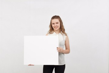 Young woman holding blank poster.Smiling woman sign board holding. Girl showing banner with copy...