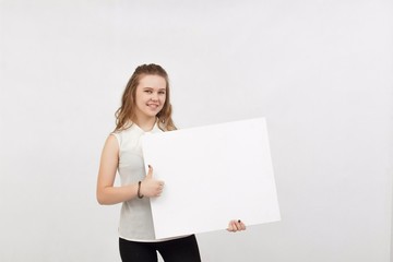 Young woman holding blank poster.Smiling woman sign board holding. Girl showing banner with copy...