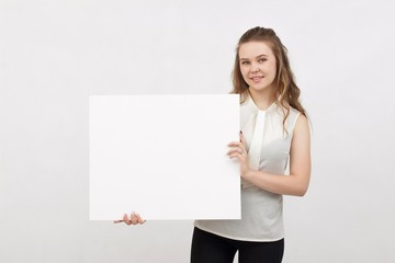 Young woman holding blank poster.Smiling woman sign board holding. Girl showing banner with copy...