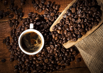 Coffee cup and sack with coffee beans on a wooden table. Top view.
