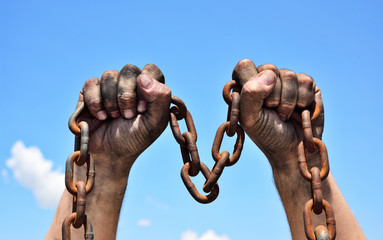 Two male hands holding a rusty metal chain
