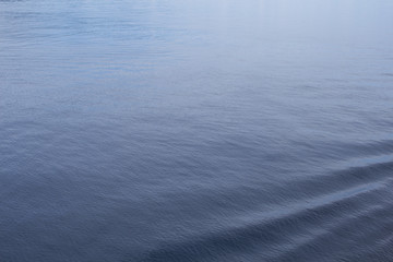 Sea water closeup with rippled surface and blue depth. Oceanic cruise liner trail in clean blue water.