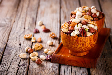 Nuts Mixed in a wooden plate.Assortment, Walnuts,Pecan,Almonds,Hazelnuts,Cashews,Pistachios.Concept of Healthy Eating.Vegetarian.Copy space.selective focus.