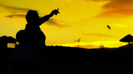Fototapeta na wymiar mother and your son flying kite at sunrise