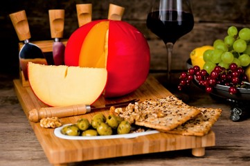 Assortment of tasty cheeses and fruits on a wooden background