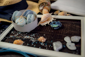 Blue and sea blue macaroons in a marine theme on a dark background decorated with rope and sea salt.