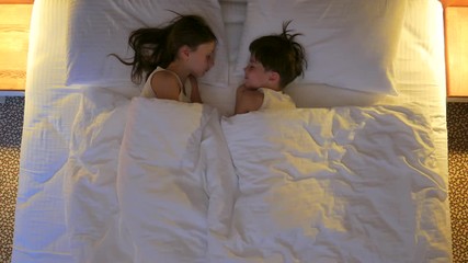 A boy and a girl are sleeping in a bed. View from above.