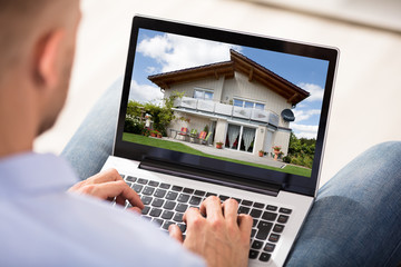 Man Looking At House Exterior On Laptop