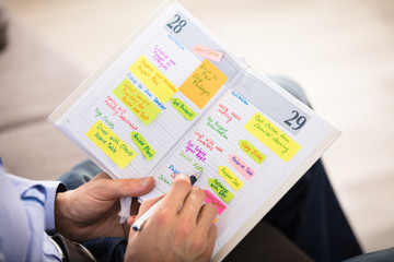 Man Writing Important Notes In Diary