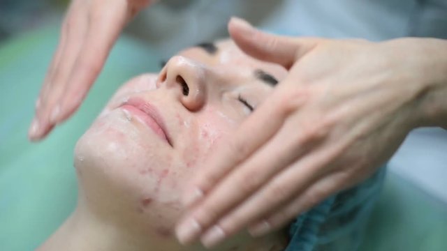 Cosmetologist cream to the face and massages woman having cosmetic treatment at spa. Professional beautician applying mask on female at beauty salon. Skin facial procedures cleaning Cosmetology.