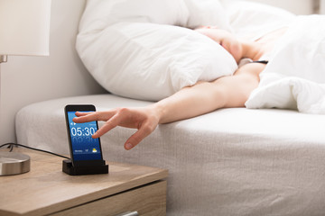 Fototapeta premium Sleepy Woman Snoozing Alarm On Phone