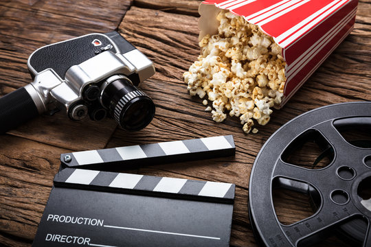 Movie Camera With Clapper Board And Popcorn On Wood