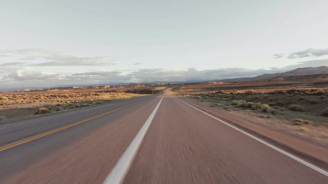 Driving USA: Beautiful point of view shot driving on long straight road in desert grasslands at sunrise/sunset, Wyoming