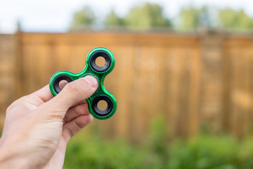 A boy plays with spinner twisting it in his hand on outdoors. Trends in children's anti-stress toys