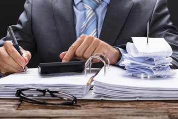 Businessman Calculating Invoice With Bill Stand On Documents