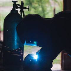 Fototapeta premium The silhouette of a welder, a tank of oxygen,