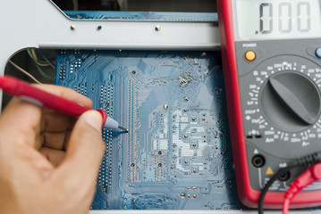 Electrical engineer checking circuit board by digital multimeter.