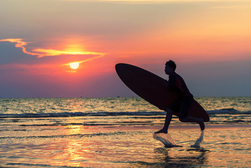 Man running with surfboard on the beach.