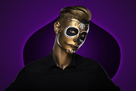 The guy with the painted golden face for Halloween. Masquerade Party. Night festivities dressed as zombies. Face art
